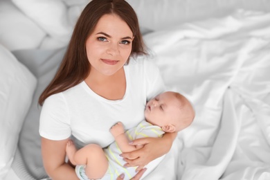 Mother with her sleeping baby in bed at home