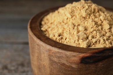 Photo of Bowl of mustard powder on wooden table, closeup