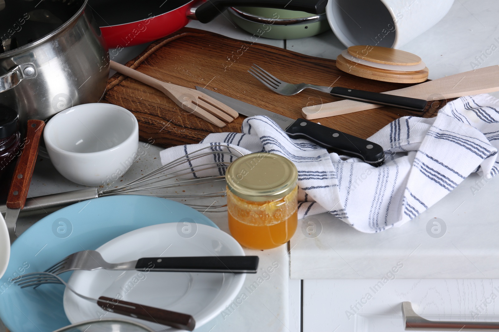 Photo of Many dirty utensils and dishware on countertop in messy kitchen