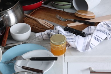 Many dirty utensils and dishware on countertop in messy kitchen