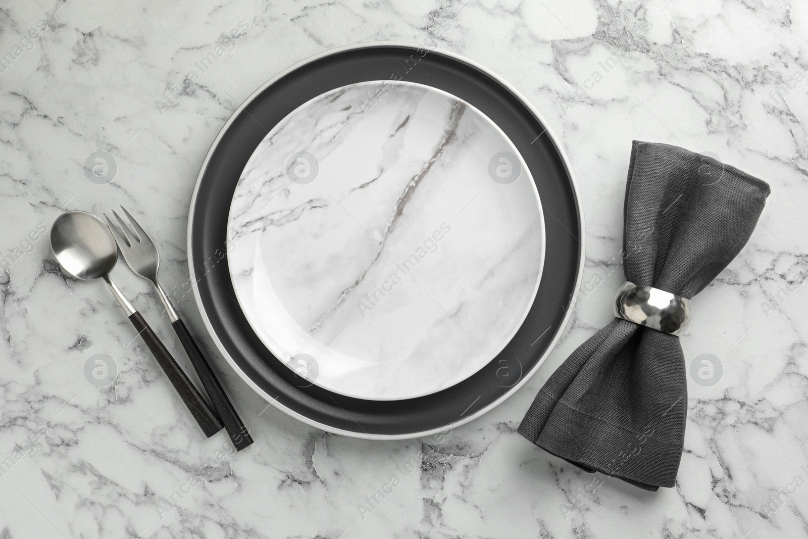 Photo of Stylish setting with cutlery, napkin and plates on white marble table, top view