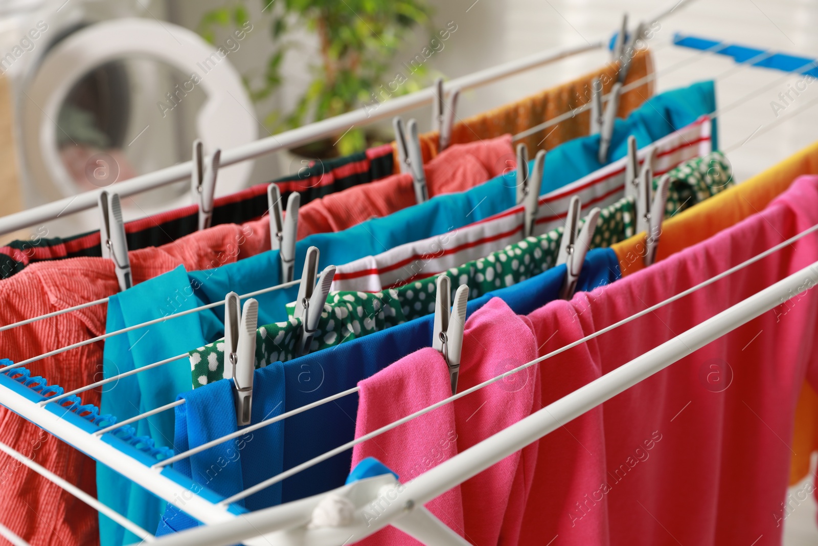 Photo of Clean laundry hanging on drying rack indoors, closeup