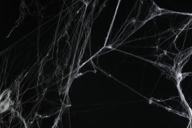 Photo of Creepy white cobweb on black background, closeup