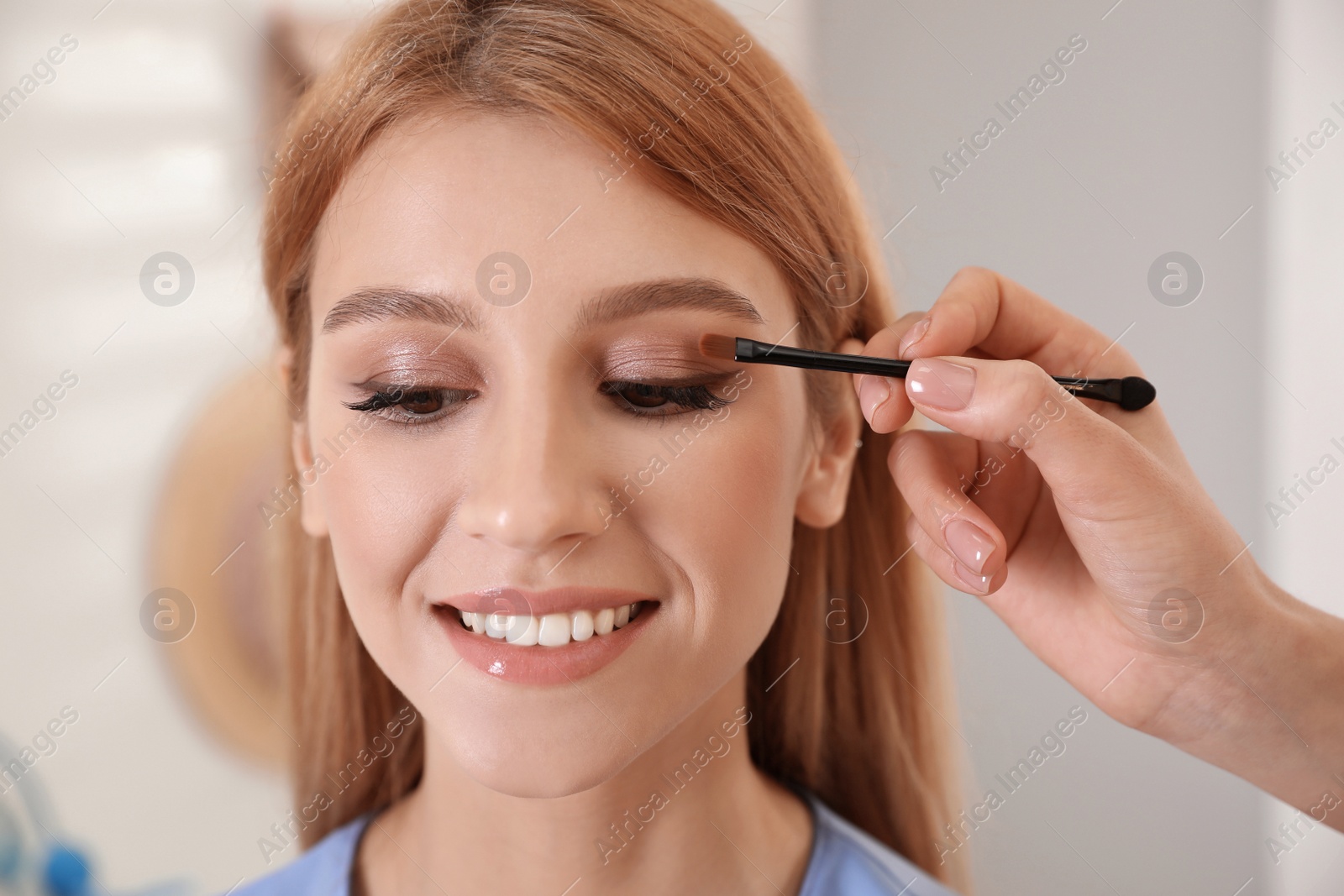 Photo of Professional makeup artist working with beautiful woman in salon