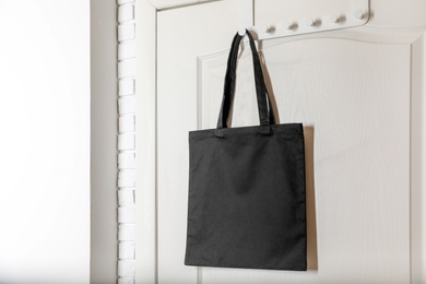 Photo of Eco tote bag hanging on door. Space for design