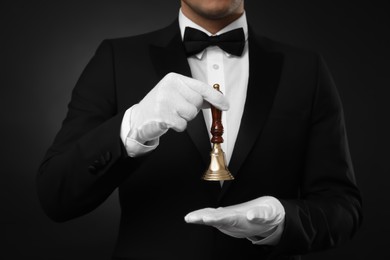 Photo of Butler holding hand bell on black background, closeup