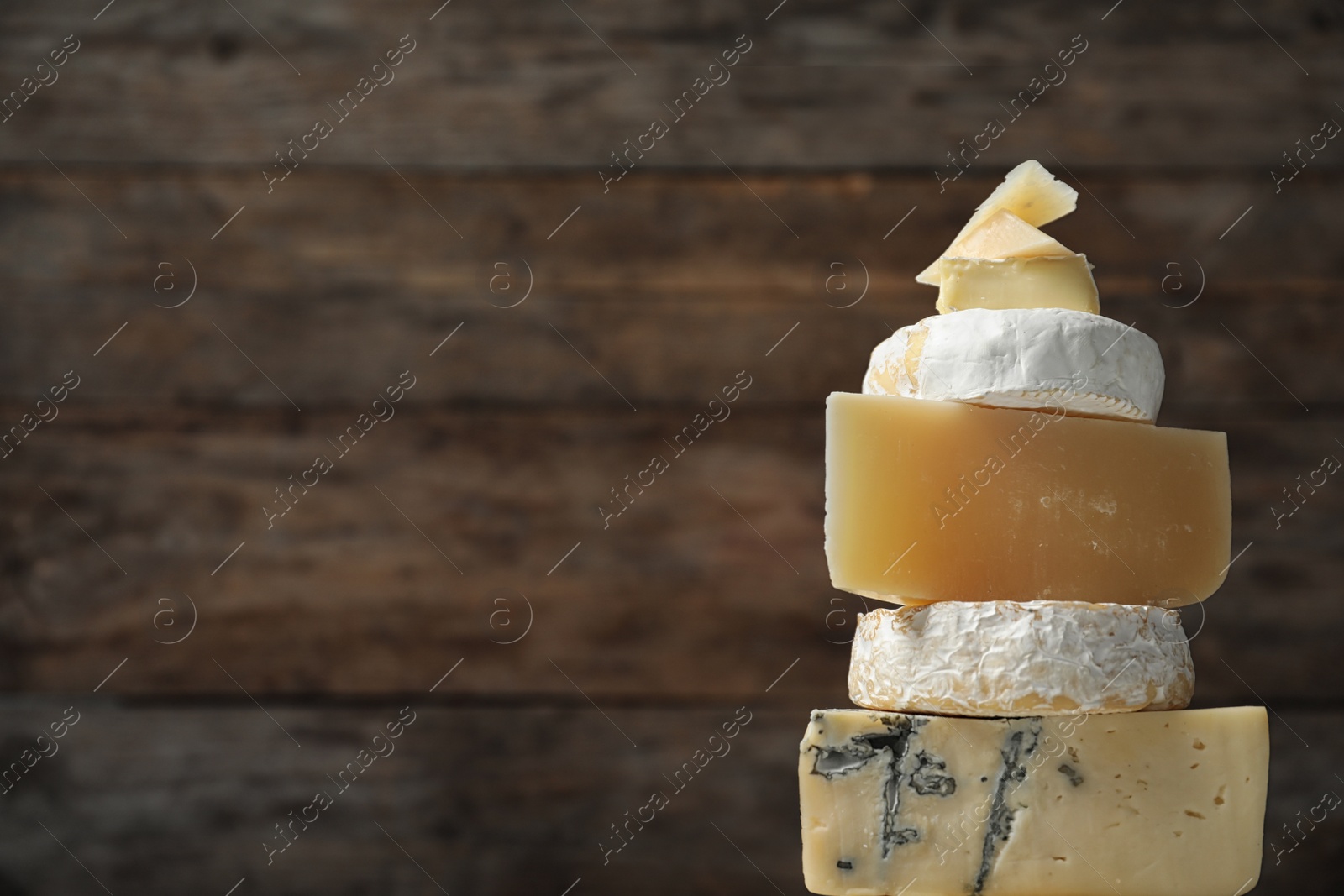 Photo of Different types of delicious cheese against wooden background, closeup. Space for text