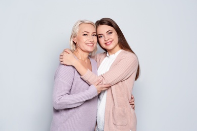 Portrait of mature woman and her daughter on color background