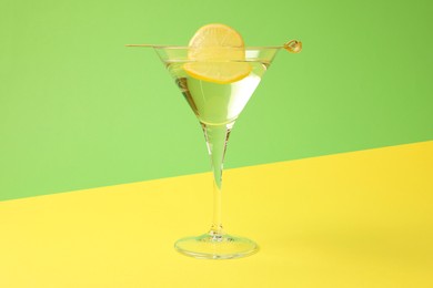 Martini glass of refreshing cocktail with lemon slice on color background