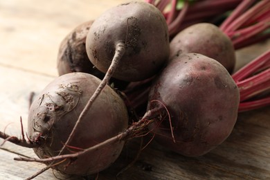 Photo of Raw ripe beets on wooden table, closeup