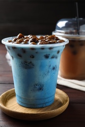 Tasty blue milk bubble tea on brown wooden table, closeup