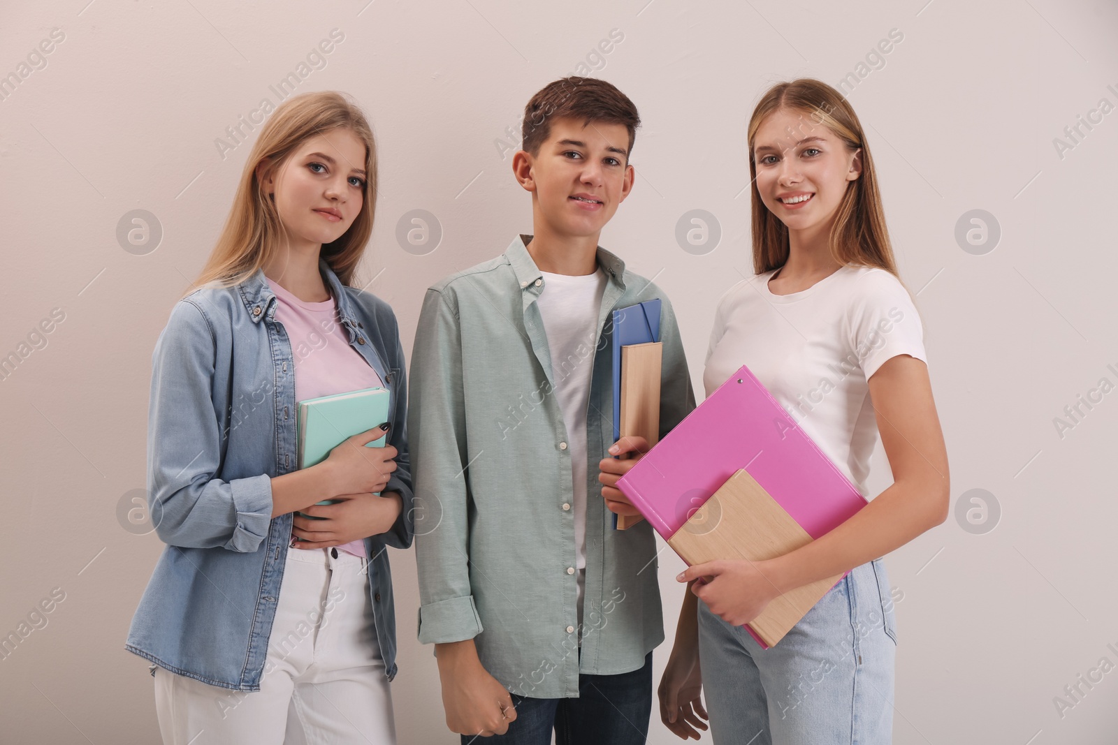 Photo of Group of teenage students with stationery on beige background