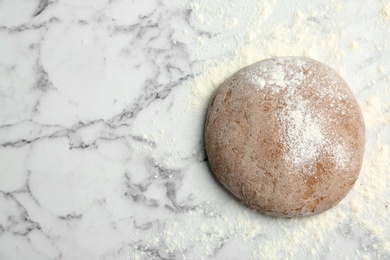 Fresh rye dough with flour on marble background, top view