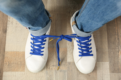 Photo of Man wearing sneakers with tied together laces, top view. April fool's day