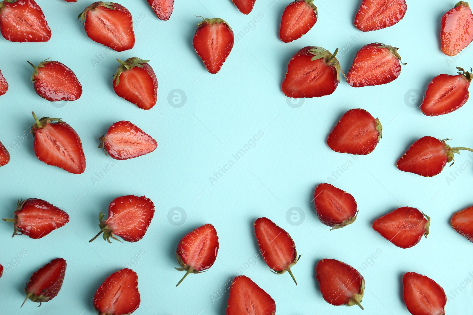 Photo of Halves of delicious ripe strawberries on light blue background, flat lay