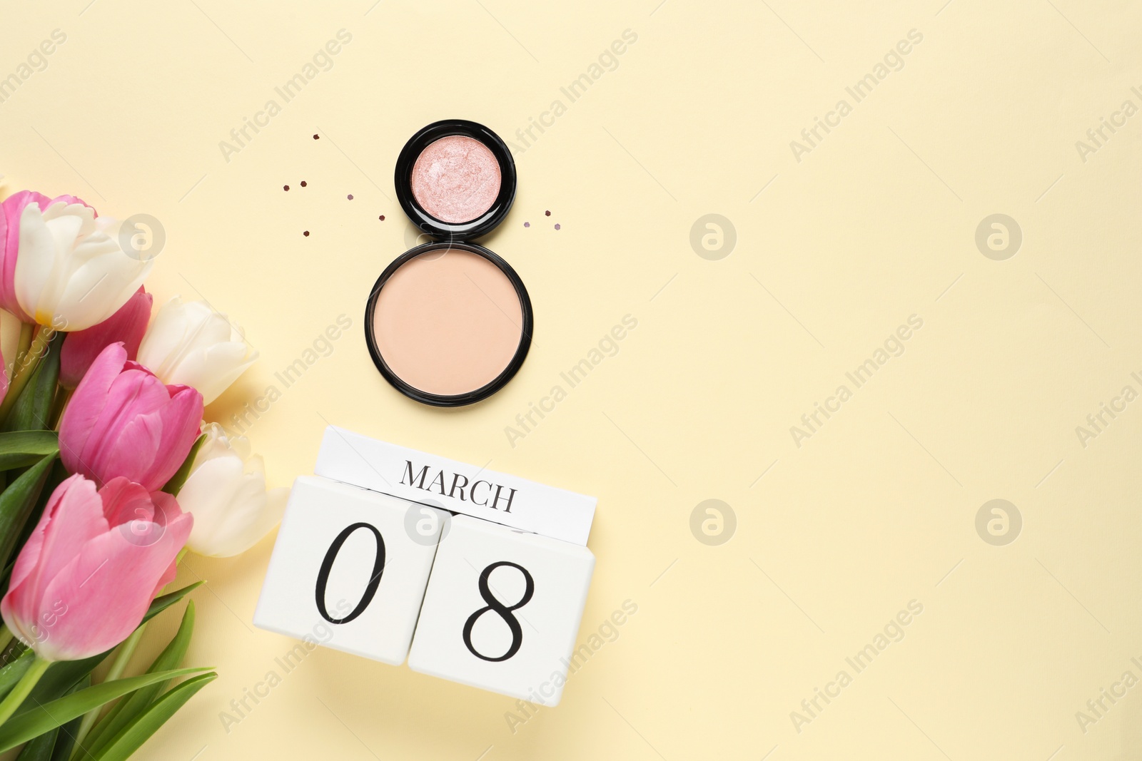 Photo of International Women's day - 8th of March. Cosmetic products, wooden block calendar, beautiful flowers on beige background, flat lay. Space for text