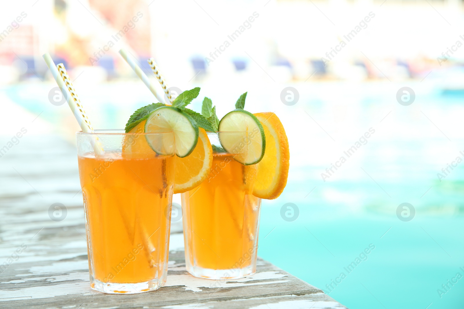 Photo of Refreshing cocktail in glasses near outdoor swimming pool on sunny day