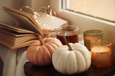 Photo of Beautiful pumpkins and candles on window sill indoors