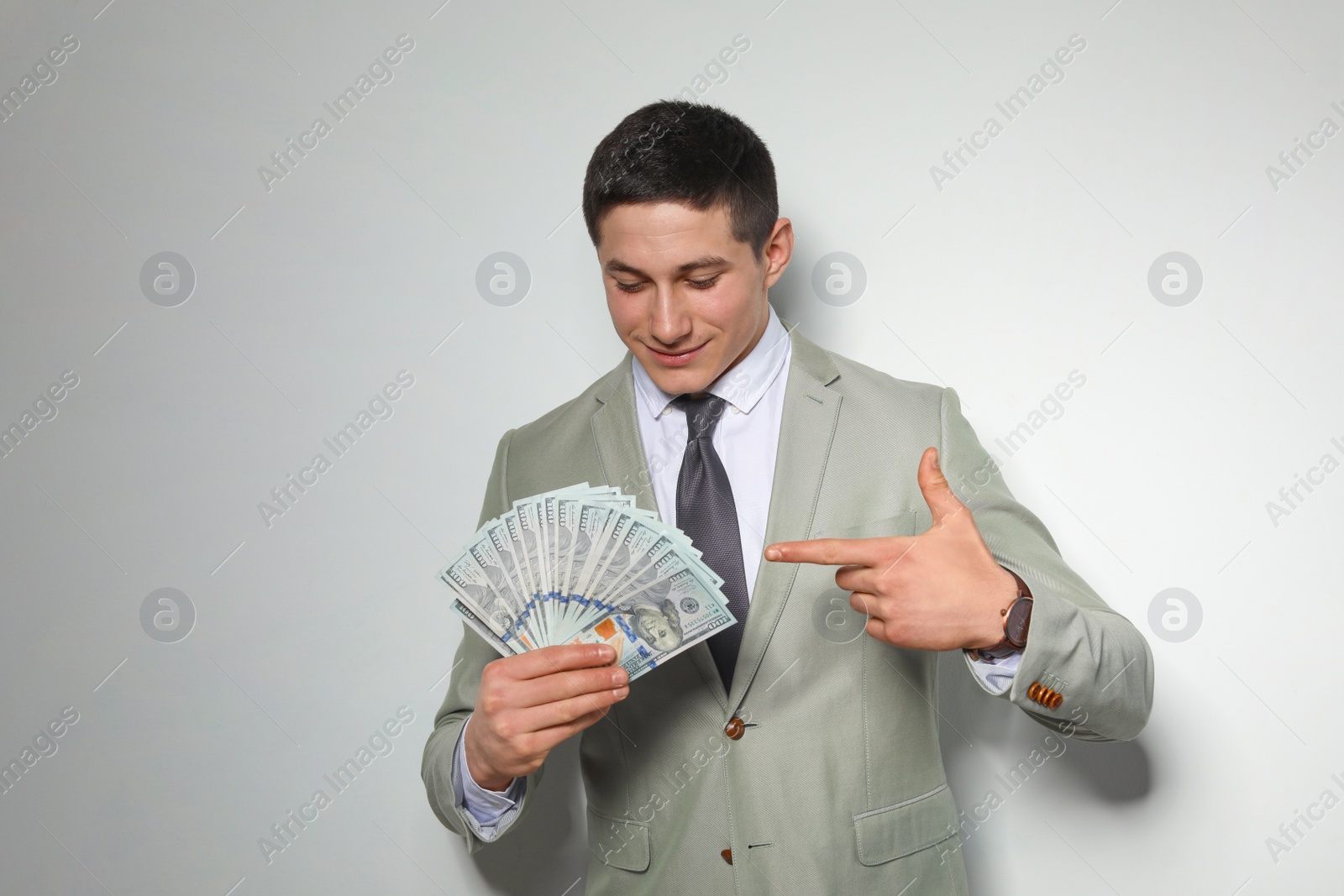 Photo of Portrait of young businessman with money fan on light background