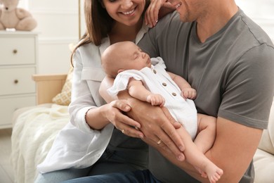 Photo of Happy couple holding their sleeping baby at home, closeup