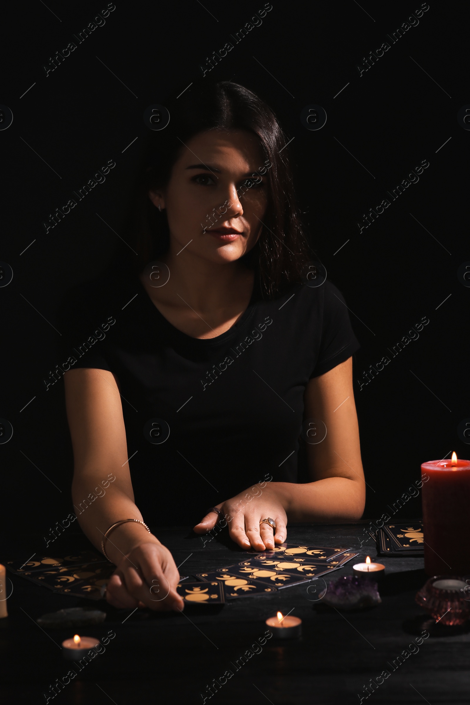 Photo of Soothsayer predicting future with tarot cards at table in darkness