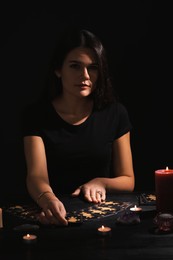 Photo of Soothsayer predicting future with tarot cards at table in darkness