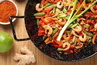 Shrimp stir fry with vegetables in wok and ingredients on table, flat lay