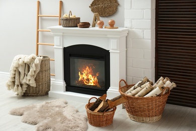 Photo of Wicker baskets with firewood and white fireplace in cozy living room