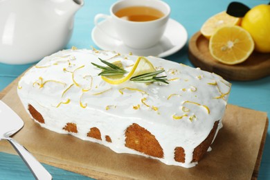 Photo of Tasty lemon cake with glaze on light blue wooden table, closeup