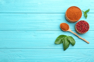 Photo of Flat lay composition of red powdered pepper and corns on blue wooden table, space for text