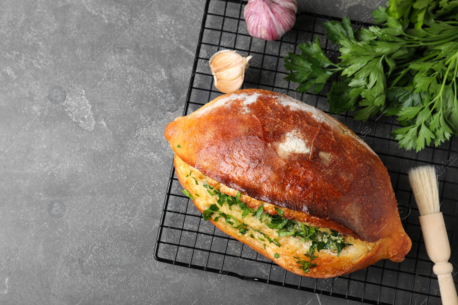 Photo of Delicious homemade garlic bread with herbs on grey table, top view. Space for text