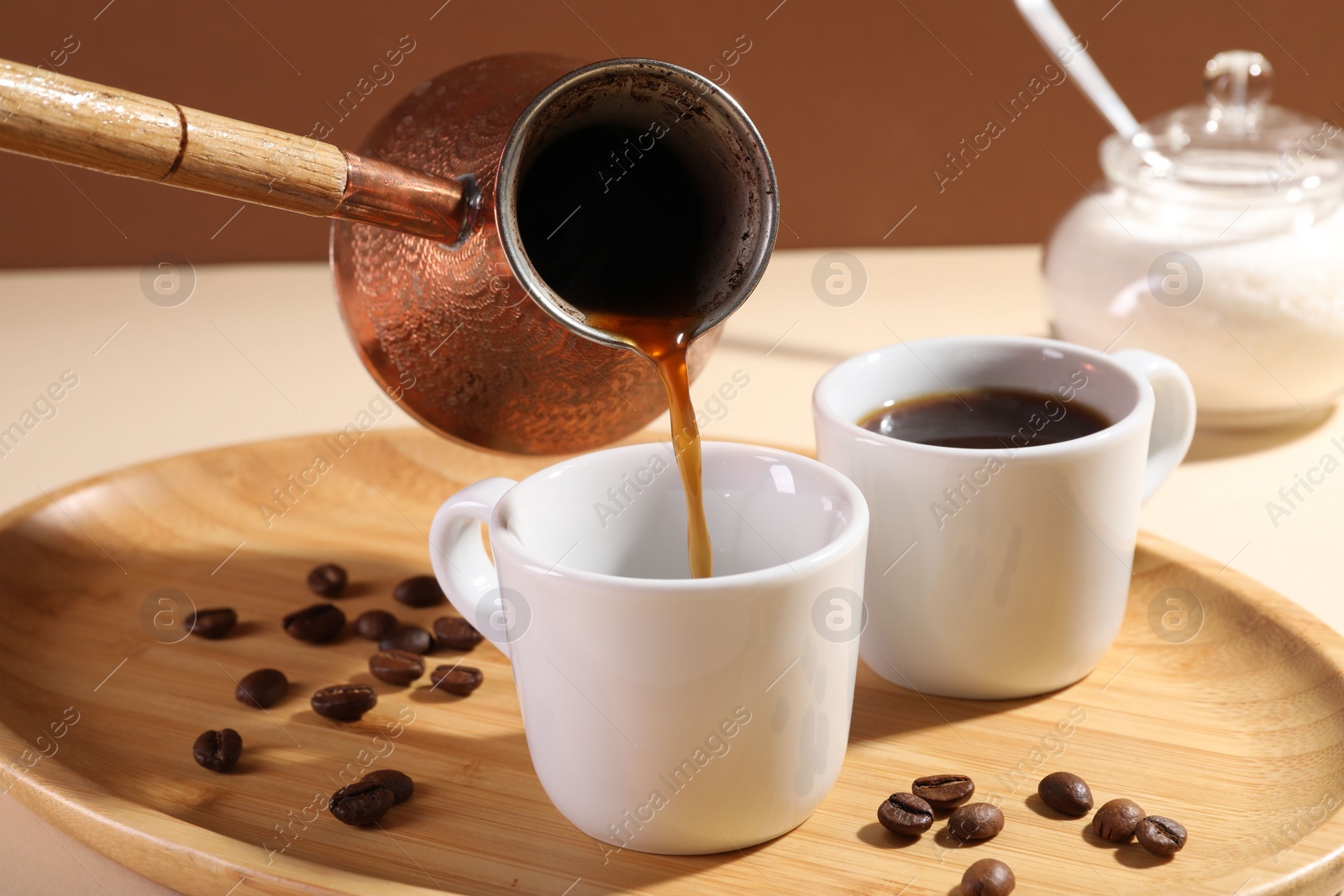 Photo of Pouring aromatic coffee from cezve into cup at table, closeup