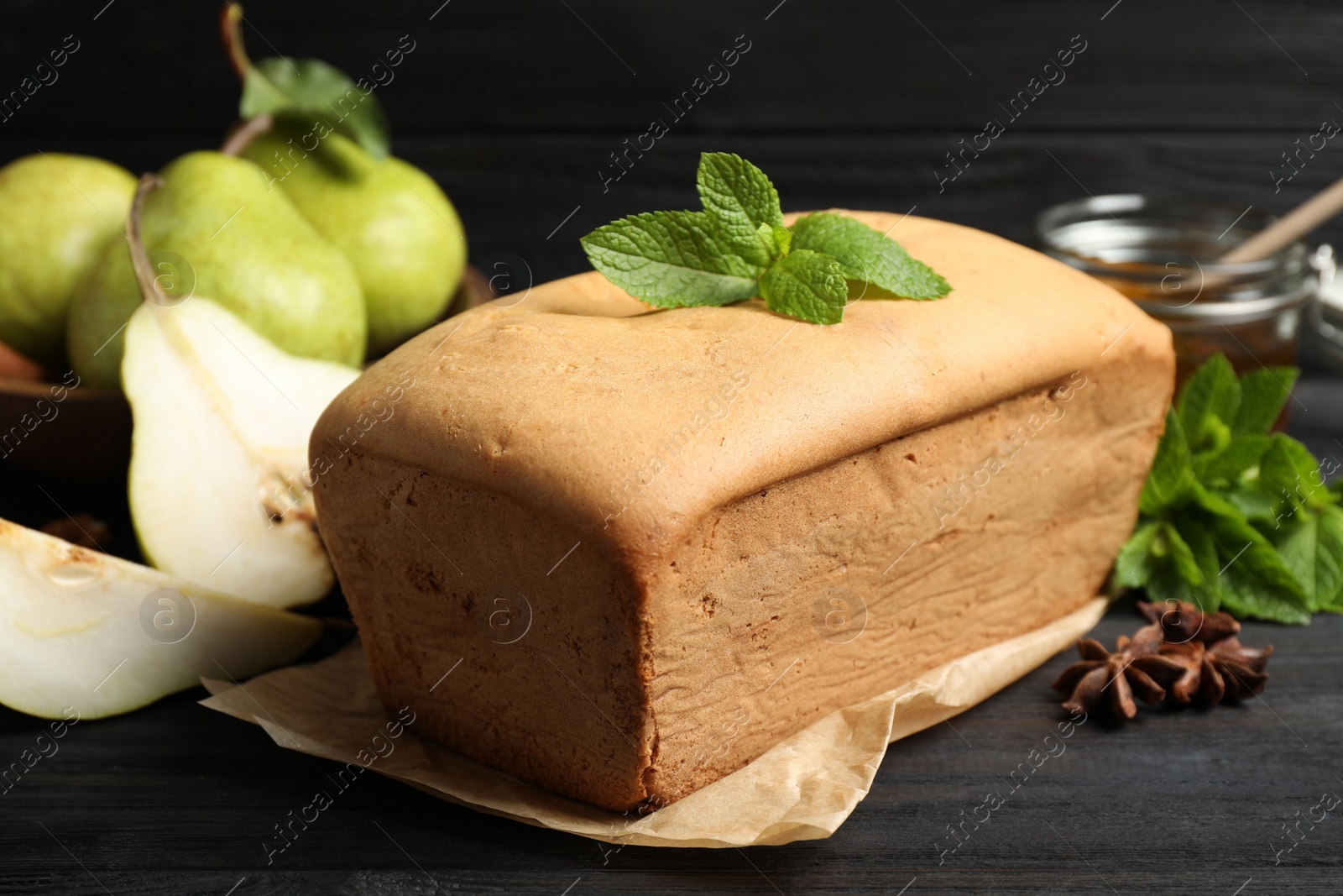 Photo of Tasty pear bread and mint on black wooden table, closeup. Homemade cake