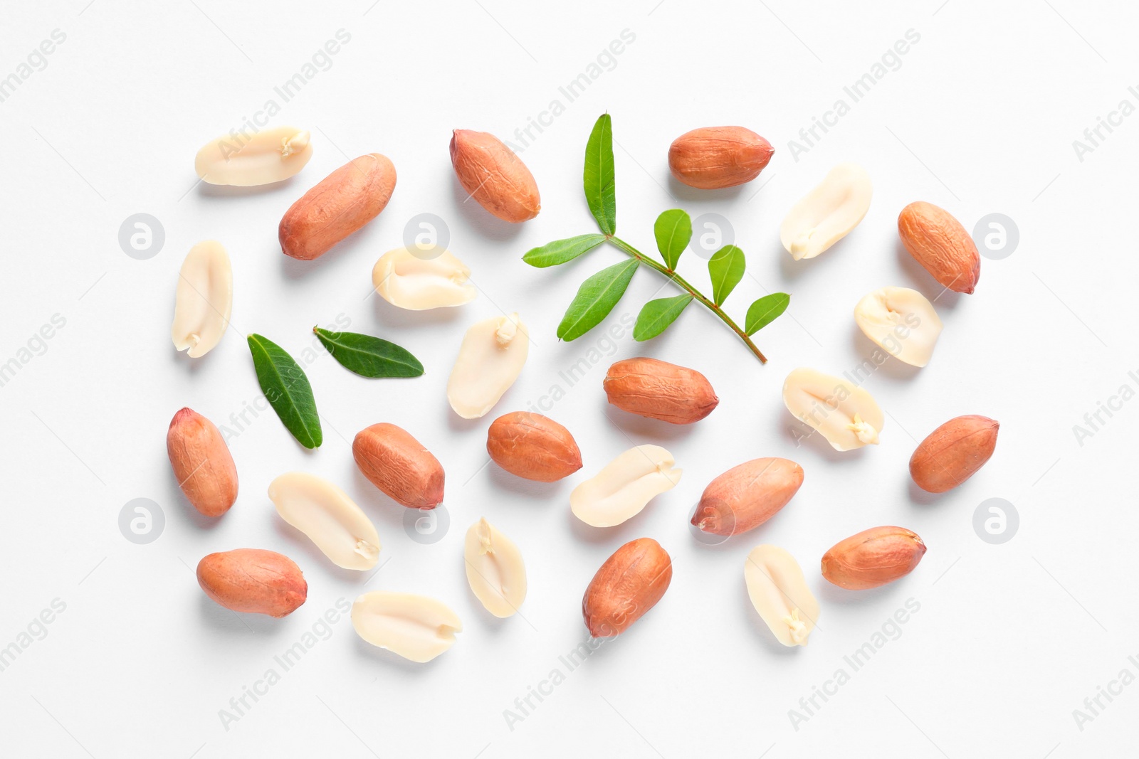 Photo of Fresh peanuts and green leaves on white background, flat lay