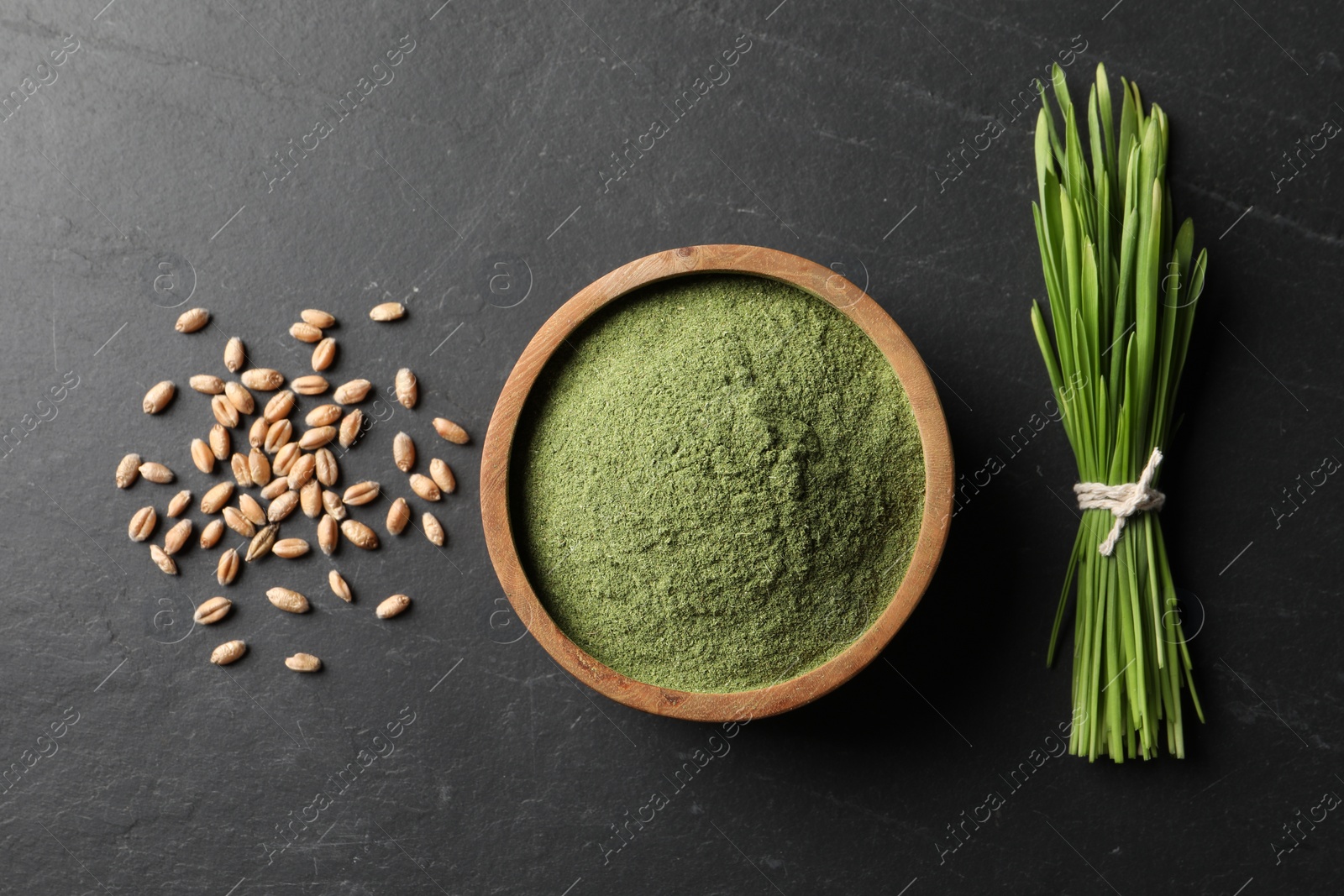 Photo of Wheat grass powder in bowl, seeds and fresh sprouts on grey textured table, flat lay
