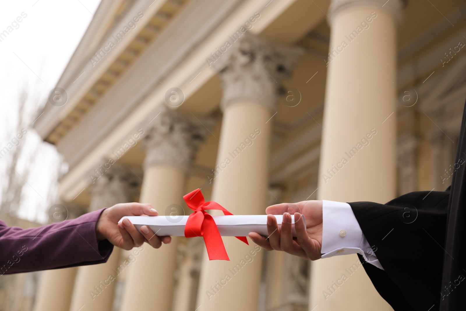 Photo of Student receiving diploma during graduation ceremony outdoors, closeup