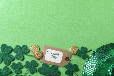 Photo of Clover leaves and tag with phrase St. Patrick's Day on light green background, flat lay. Space for text