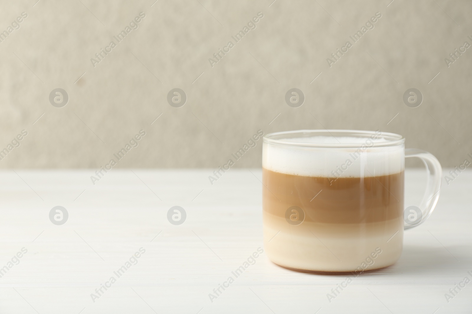 Photo of Aromatic coffee in glass cup on white wooden table, space for text
