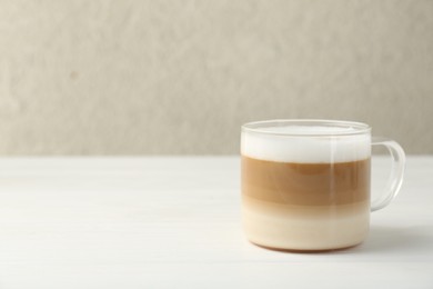 Aromatic coffee in glass cup on white wooden table, space for text