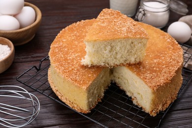 Tasty sponge cake and ingredients on wooden table, closeup