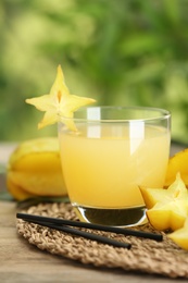 Photo of Delicious carambola juice and fresh fruits on wooden table against blurred background