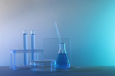 Photo of Laboratory analysis. Different glassware on table against color background, space for text