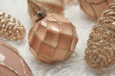 Photo of Collection of beautiful Christmas tree baubles on white faux fur, closeup