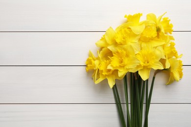 Photo of Beautiful daffodil bouquet on white wooden table, top view. Space for text