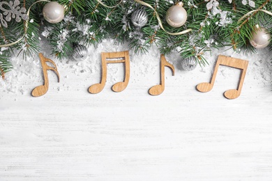 Flat lay composition with Christmas decor and music notes on white wooden table, space for text