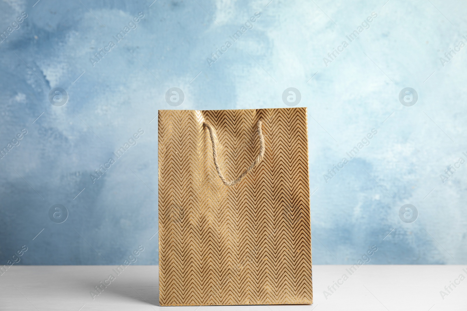 Photo of Gold shopping paper bag on white table