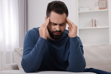 Man suffering from headache on sofa at home