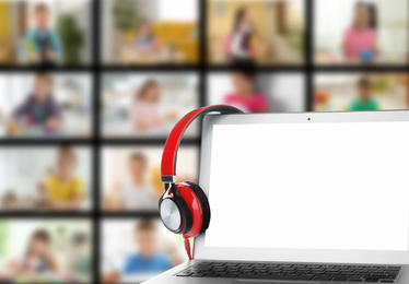 Distance education during coronavirus quarantine, online classroom. Modern laptop and headphones against blurred background