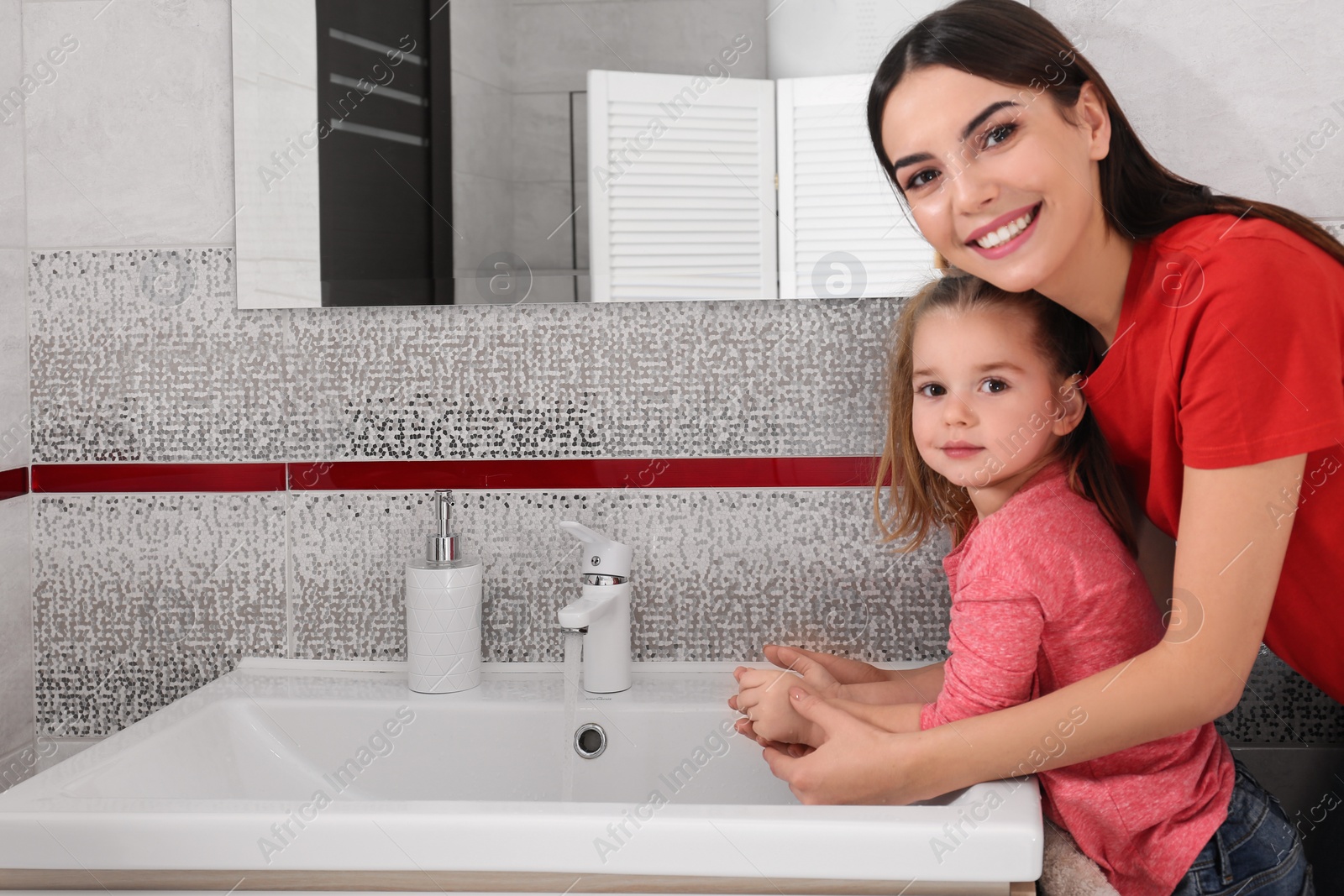 Photo of Happy mother and daughter washing hands in bathroom at home