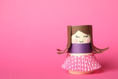 Toy doll made of toilet paper hub on pink background. Space for text
